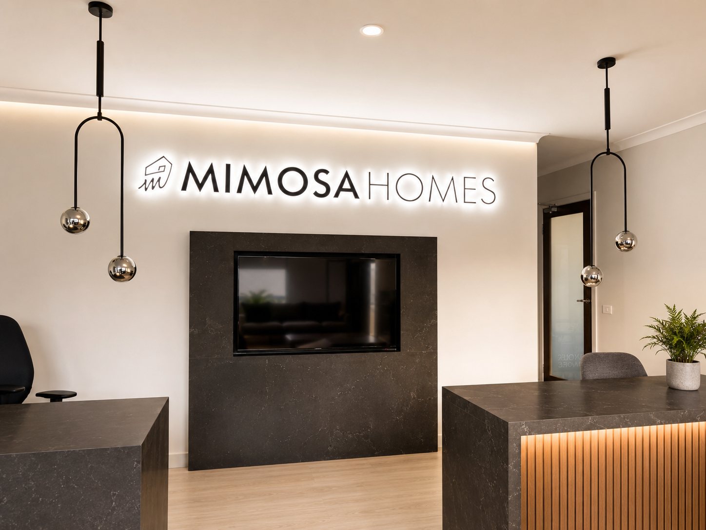 Halo-lit reception logo letters above a stone feature wall with a mounted screen