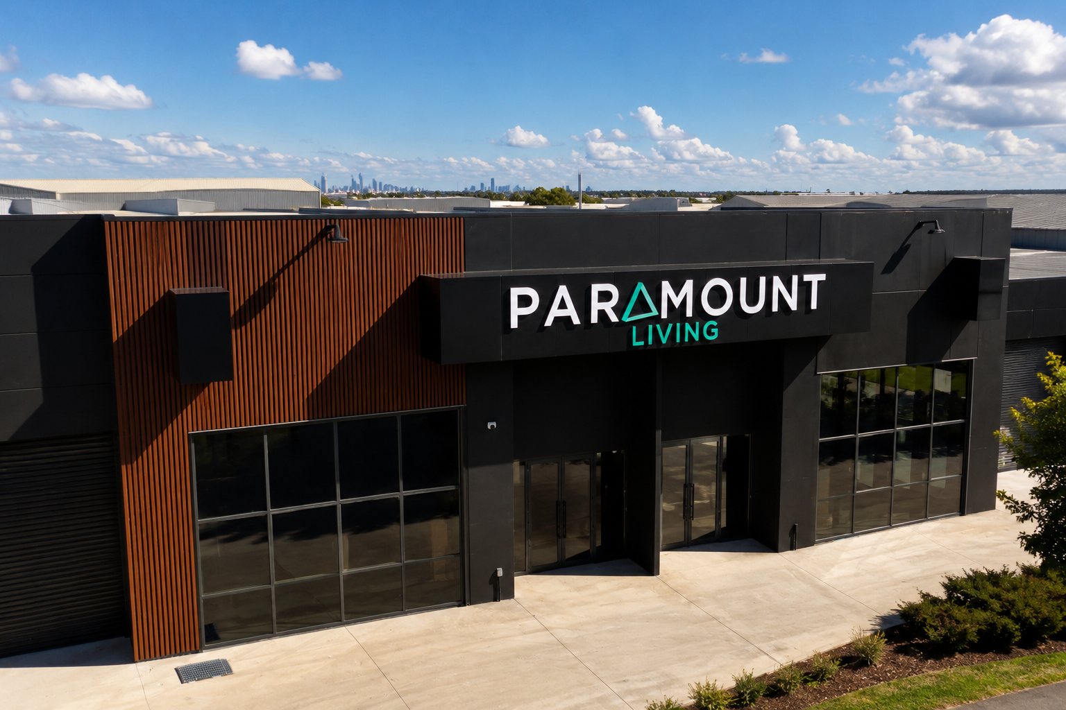 Dimensional fascia lettering on a black showroom facade with the Melbourne skyline behind
