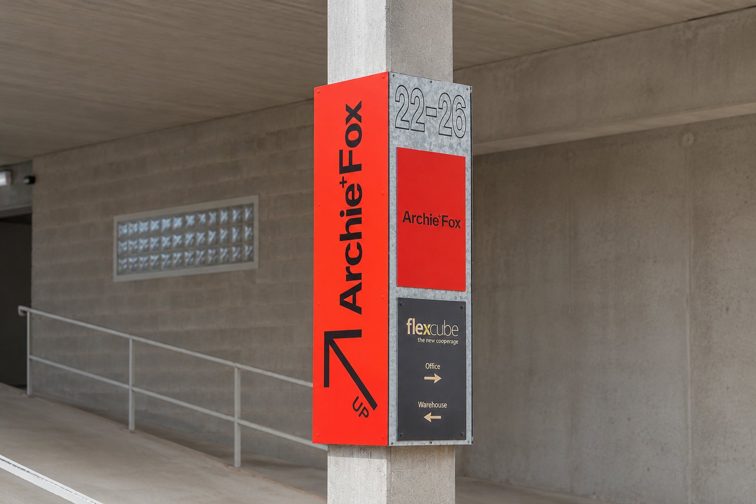Red and galvanised column-wrap wayfinding sign with tenant logos in a car park
